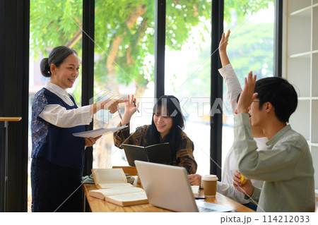 Active college students raising hands to answer teacher's question during class 114212033