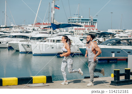 Young sporty couple running over wooden pier at sunset 114212181