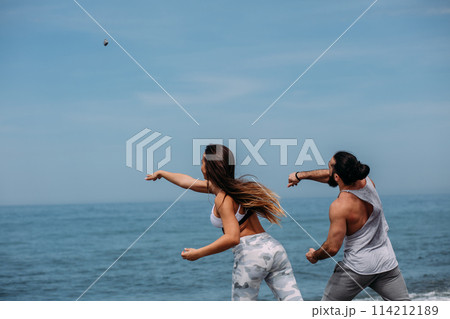 Young fitness couple embracing standing on beach, looking at horizon Young fitness couple embracing standing on beach, looking at horizon 114212189
