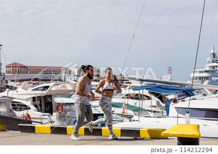 Young sporty couple running over wooden pier at sunset 114212294