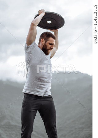 Handsome muscular hunk man looking at mountains from the peak. 114212315