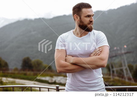 Handsome muscular hunk man looking at mountains from the peak. 114212317
