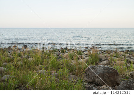 Summer evening on a lake shore with big stones Summer evening on a lake shore with big stones 114212533