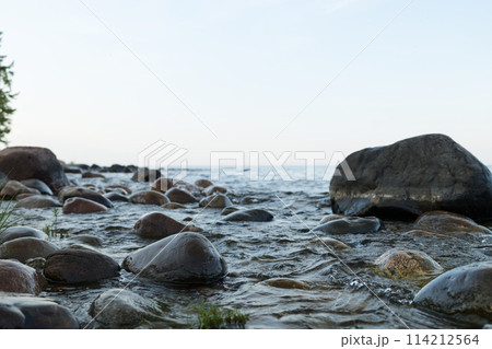 Summer evening on a lake shore with big stones Summer evening on a lake shore with big stones 114212564