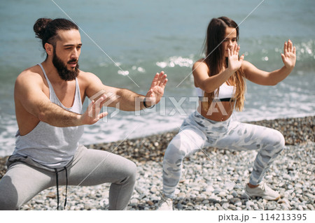 Couple warming out outdoors, doing squats together 114213395