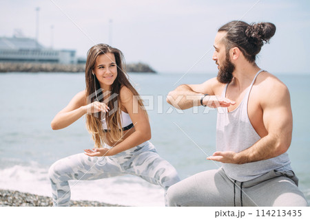 Couple warming out outdoors, doing squats together 114213435