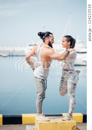 Young beautiful couple doing stretching exercises at the ocean pier 114213519