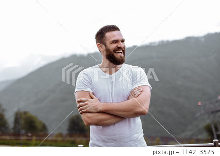 Handsome muscular hunk man looking at mountains from the peak. 114213525