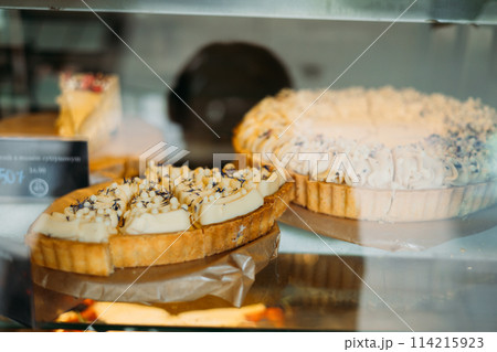 Showcase with cakes in the store. Small business, food concept. Lots of pastries in pastry shop. Many delicious cakes in the shop window of a cozy cafe Showcase with cakes in the store. Small business, food concept. Lots of pastries in pastry shop. Many delicious cakes in the shop window of a cozy cafe 114215923