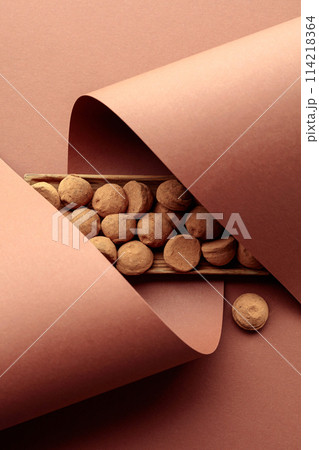 Tasty chocolate truffles in a wooden dish on a brown background. 114218364