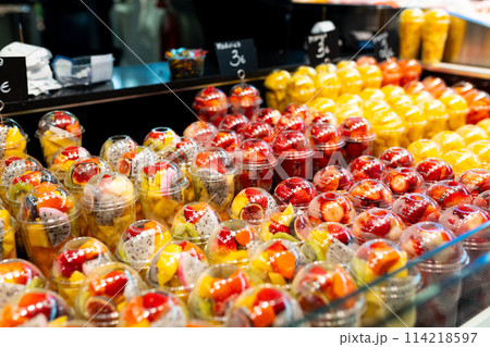 Fruit Salad arranged in plastic cups on a market. Cut and ready fruit ready to sell in market. Convenience, healthy lifestyle. Strawberries, kiwi, melon, pineapple, figs, dragon in a plastic glass. 114218597