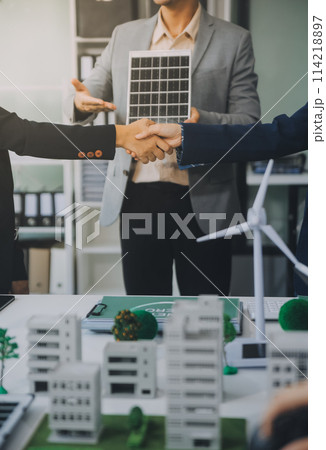 Two business executives, elegantly attired in suits, join hands in a gesture of unity, solidarity, and shared commitment towards a common goal or venture. 114218897