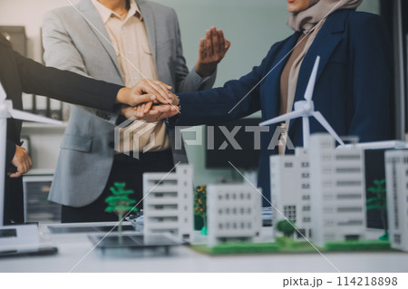 Two business executives, elegantly attired in suits, join hands in a gesture of unity, solidarity, and shared commitment towards a common goal or venture. Two business executives, elegantly attired in suits, join hands in a gesture of unity, solidarity, and shared commitment towards a common goal or venture. 114218898