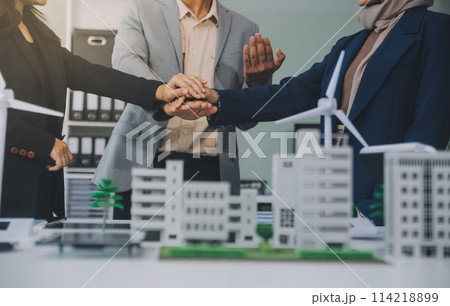 Two business executives, elegantly attired in suits, join hands in a gesture of unity, solidarity, and shared commitment towards a common goal or venture. Two business executives, elegantly attired in suits, join hands in a gesture of unity, solidarity, and shared commitment towards a common goal or venture. 114218899