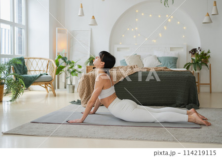 Yoga fitness workout training. Woman practicing yoga at home. Woman doing sports exercise on yoga mat on floor indoor. Girl in sportswear have training workout for weight loss. Sport and fitness Yoga fitness workout training. Woman practicing yoga at home. Woman doing sports exercise on yoga mat on floor indoor. Girl in sportswear have training workout for weight loss. Sport and fitness 114219115