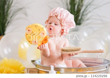 Bath time for baby, child sitting in a basin with rubber ducks 114220266