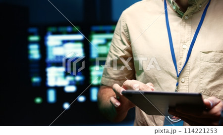 Serviceman doing system analysis, typing data on tablet of needed adjustments in supercomputers server hub housing advanced data storage infrastructure supporting critical IT workloads, close up 114221253