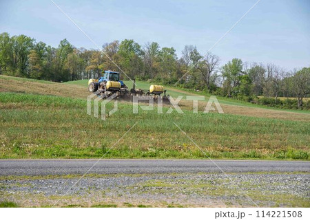Tractor pulls planter with fertilizer tanks plants hillside farm field Tractor pulls planter with fertilizer tanks plants hillside farm field 114221508
