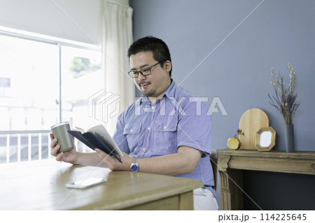 休日に自宅で本を読む大柄な日本人男性 114225645