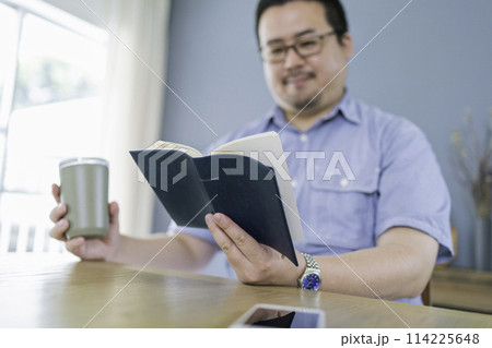 休日に自宅で本を読む大柄な日本人男性 休日に自宅で本を読む大柄な日本人男性 114225648