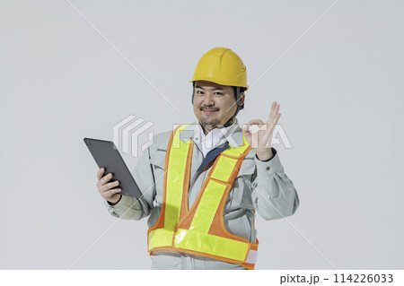 タブレット端末を持ってOKサインをする作業服の男性 114226033