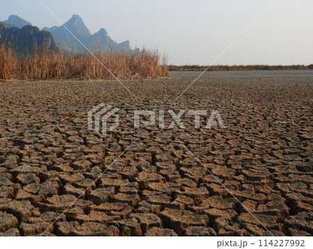 Scorched earth soil drought desert landscape dramatic with mountain in background, Global warming concept , Wetland dry and become cracked land at Khao Sam Roi Yot National Park , Thailand 114227992