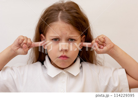 Portrait of caucasian child close ears by fingers on white background Portrait of caucasian child close ears by fingers on white background 114229395