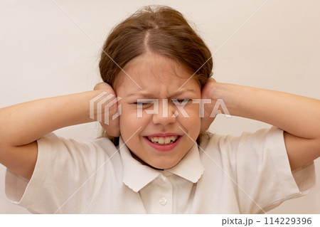 Portrait of caucasian child close ears by hands on white background Portrait of caucasian child close ears by hands on white background 114229396