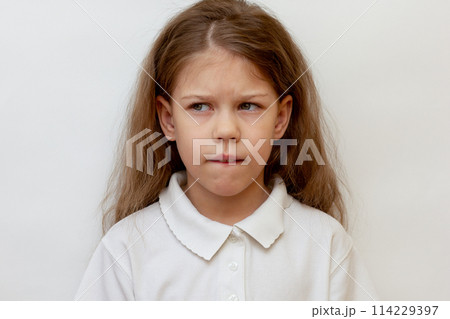 Portrait of caucasian child biting lower lip on white background Portrait of caucasian child biting lower lip on white background 114229397