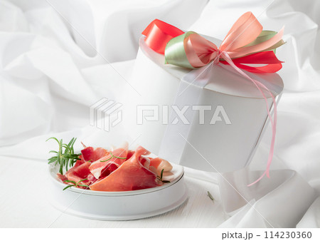 Prosciutto with rosemary in gift box on a white wooden table. 114230360