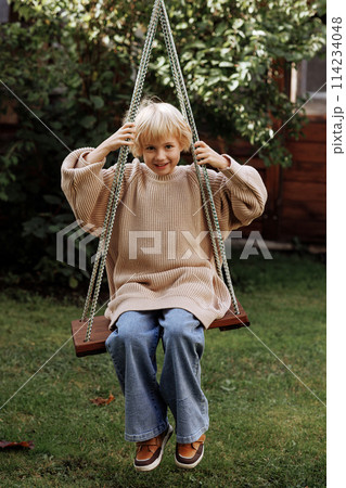 Child girl swinging on a swing on the backyard at home 114234048