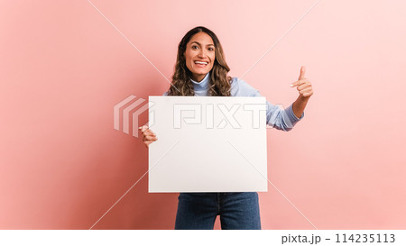Woman holding a blank panel and pointing around 114235113
