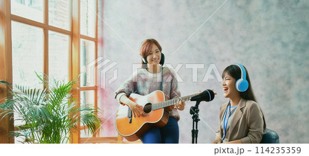 フォークギターを弾く女性とシャウトする女性ボーカリスト1  114235359