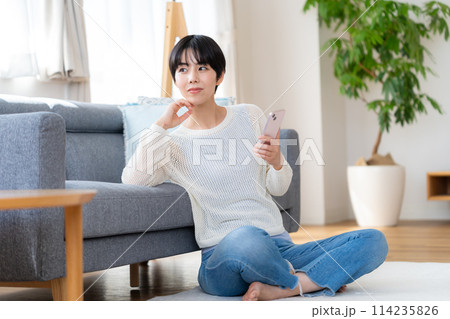 部屋でスマホを操作する女性 114235826
