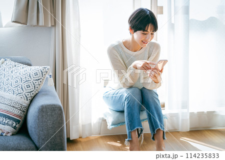 部屋でスマホを操作する女性 部屋でスマホを操作する女性 114235833