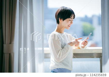 部屋でスマホを操作する女性 114235839