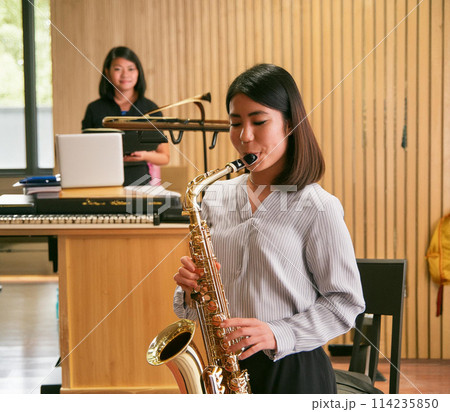 アルトサックスを吹く女性と教えている女性講師1 114235850