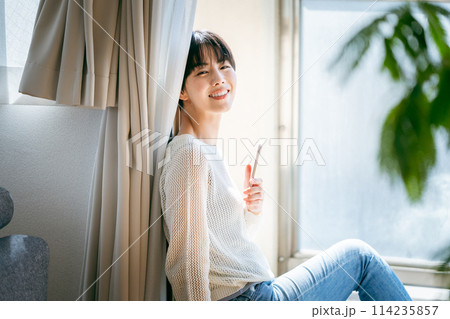部屋でスマホを操作する女性 部屋でスマホを操作する女性 114235857