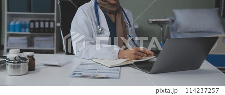 Female doctor sitting at desk and writing a prescription for her patient Female doctor sitting at desk and writing a prescription for her patient 114237257