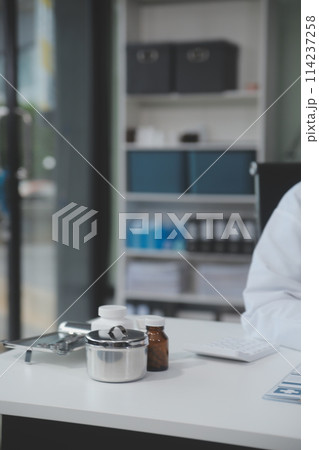 Female doctor sitting at desk and writing a prescription for her patient Female doctor sitting at desk and writing a prescription for her patient 114237258