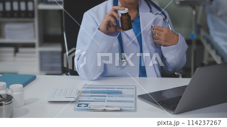 Cropped view of doctor in white coat holding bottle medication, prescribing pills to sick patient via online consultation. Family therapist recommend quality medicines. Healthcare, treatment concept Cropped view of doctor in white coat holding bottle medication, prescribing pills to sick patient via online consultation. Family therapist recommend quality medicines. Healthcare, treatment concept 114237267
