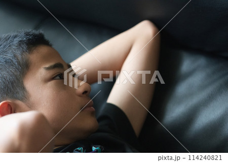 ソファーで寝転ぶ少年 114240821