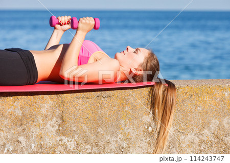 Woman doing sports outdoors with dumbbells Woman doing sports outdoors with dumbbells 114243747