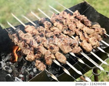 Raw meat are prepared on the metal skewers on the coals on the grill outdoors in the summer. Close-up 114244346