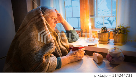 Woman warming herself by a candle in blackout Woman warming herself by a candle in blackout 114244731