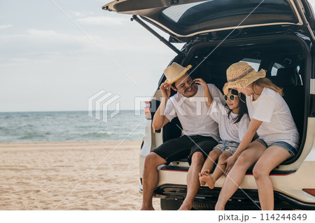 Happy Family Day. Dad, mom and daughter enjoying road trip sitting on back car, Parents and children traveling in holiday at sea beach, family having fun in summer vacation on beach with automobile Happy Family Day. Dad, mom and daughter enjoying road trip sitting on back car, Parents and children traveling in holiday at sea beach, family having fun in summer vacation on beach with automobile 114244849