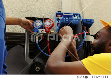 Seasoned mechanics commissioned by client to do maintenance on hvac system, repairing broken manifold gauges. Precise servicemen refilling freon tank after patching up leak Seasoned mechanics commissioned by client to do maintenance on hvac system, repairing broken manifold gauges. Precise servicemen refilling freon tank after patching up leak 114246111