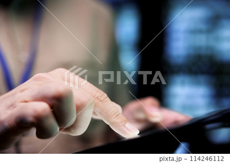 Meticulous mechaninc doing thorough system scan, typing data on tablet of needed repairs in blade servers housing advanced data storage equipment supporting complex computing operations, close up 114246112