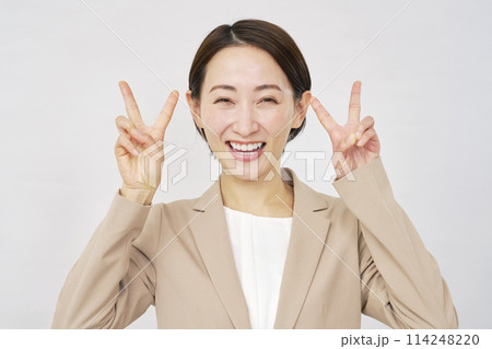 両手でピースサインするミドルエイジのビジネスウーマン　白背景 114248220