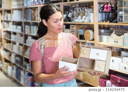 Female shopper selects wooden jewelry boxes at hardware supermarket Female shopper selects wooden jewelry boxes at hardware supermarket 114250475